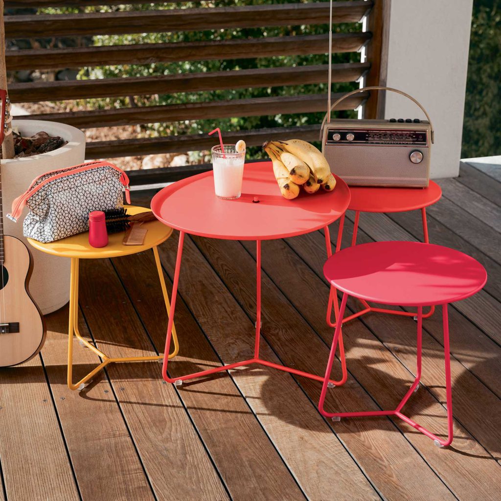 Perfektes Outdoor Living-Ensemble: vier Fermob Cocotte Beistelltische in unterschiedlichen Höhen. Drei in Rot, einer in Gelb.
